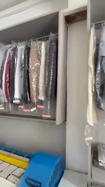 Cămăși și costume în husă, pe bara din spălătorie